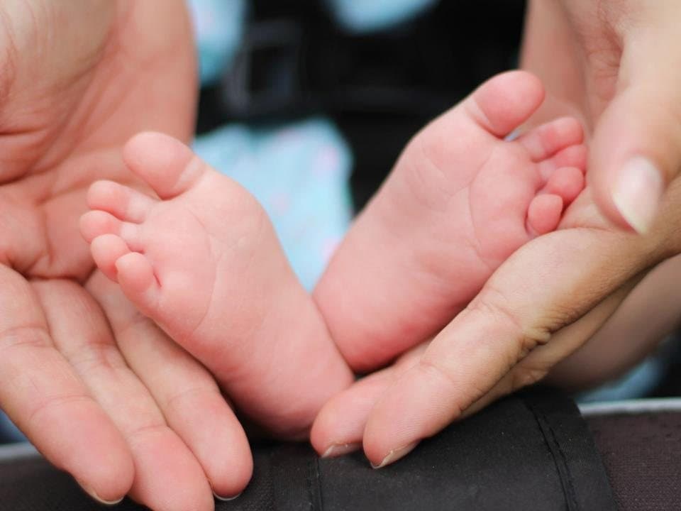 A newborn's feet held in a parent's hands